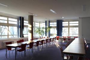 a row of tables and chairs in a room with windows at Jugendherberge-Berlin-International in Berlin