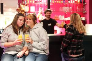 a group of women sitting in a bar holding drinks at Jugendherberge-Berlin-International in Berlin