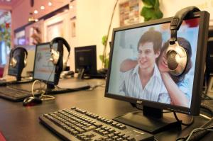 a desk with a computer monitor and a keyboard and headphones at Jugendherberge-Berlin-International in Berlin