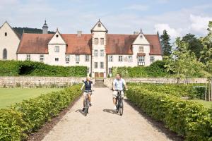 two people riding bikes down a path in front of a building at Hotel Kloster Haydau in Morschen