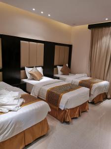 a hotel room with three beds in a room at Alwan apartment hotel in Khamis Mushayt