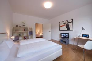 a white bedroom with a white bed and a desk at Art'Appart Suiten - kontaktloser Check-In in Berlin