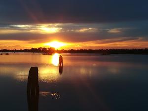 a sunset on a lake with a dock in the water at Bungalow Gambaro 2 in Cavallino-Treporti +5 photos