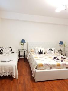 biała sypialnia z 2 łóżkami i 2 stołami w obiekcie Holiday House w mieście Castel San Giorgio