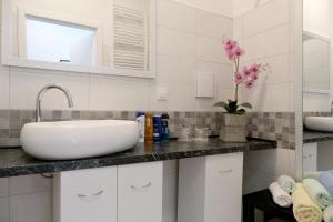 a white bathroom with a sink and a mirror at Main Square Oval Apartment in Zagreb