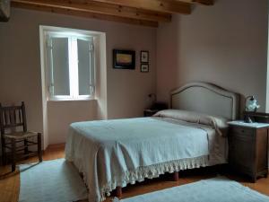 ein Schlafzimmer mit einem Bett, einem Fenster und einem Stuhl in der Unterkunft Casa Valle in Foz