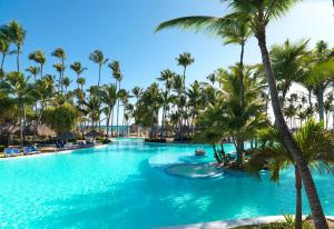 a swimming pool with palm trees in a resort at Meliá Caribe Beach Resort-All Inclusive in Punta Cana
