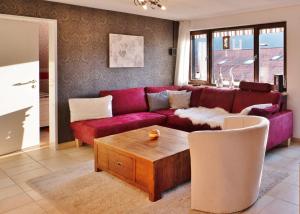 a living room with a red couch and a coffee table at Komfort-Fewo "Allgäublick" - im südlichen Kurviertel nahe Therme, Wiesen - Bergbahnen unlimited Mai-Nov in Oberstdorf