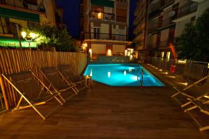a swimming pool at night with two lounge chairs at Hotel Adler in Alassio