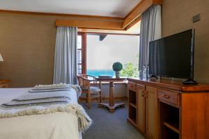 a bedroom with a bed and a flat screen tv at Hotel Puelche in Puerto Varas