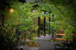 a garden with trees and a walkway at night at Oyado Den Rikyu in Yufuin