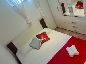 - un lit blanc avec des oreillers rouges et un miroir dans l'établissement Apartment Baćo, à Podstrana
