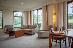 a living room with chairs and a table and windows at Yarra Valley Lodge in Wonga Park