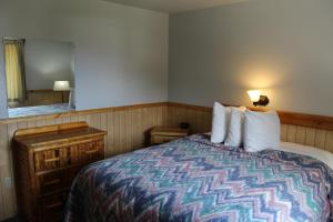 ein Hotelzimmer mit einem Bett und einem Spiegel in der Unterkunft Alpine Motel of Cooke City in Cooke City