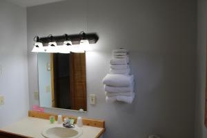 ein Badezimmer mit einem Waschbecken, einem Spiegel und Handtüchern in der Unterkunft Alpine Motel of Cooke City in Cooke City