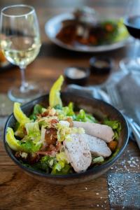 a plate of food with a salad and a glass of wine at Yarra Valley Lodge in Wonga Park