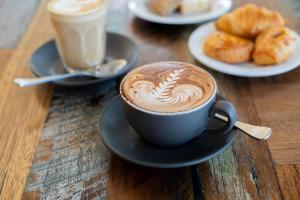 a cup of coffee on a table with plates of pastries at Yarra Valley Lodge in Wonga Park