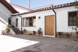 Casa blanca con puerta de madera y escaleras en Wasi, en Sucre
