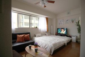 um quarto com uma cama, um sofá e uma televisão em Luft 603 em Osaka