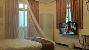 een slaapkamer met een bed en een tv aan de muur bij New Zhilan B&B in Sanzhi