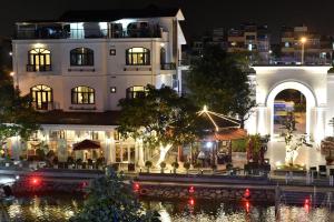duży biały budynek z rzeką przed nim w obiekcie Garco Dragon Hotel w mieście Hanoi
