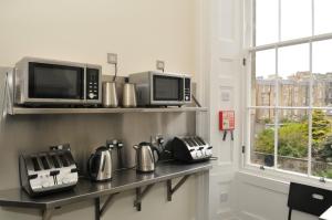 a kitchen with a microwave and appliances on a shelf at The Hostel in Edinburgh