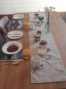 una mesa de madera cubierta con platos y tazones de comida en Pepper Tree Villa en Masterton