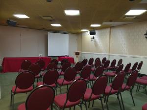 une salle de conférence avec des chaises rouges et un écran blanc dans l'établissement Hotellerie Jardins de Ville, à Sherbrooke