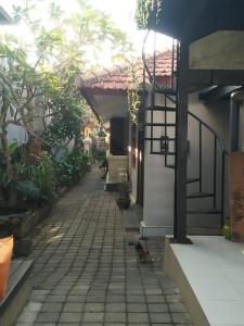 a cat walking down a sidewalk next to a house at Made House Homestay and Dormitory in Sanur