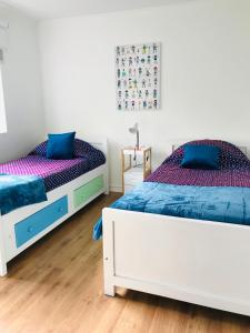 2 łóżka w białym pokoju w kolorze niebieskim i fioletowym w obiekcie Casa Boutique w mieście Chillán