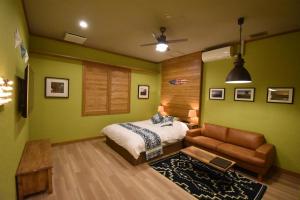 Hotel Pinon - Adult Only في Kai: غرفة نوم بجدران خضراء وسرير واريكة
