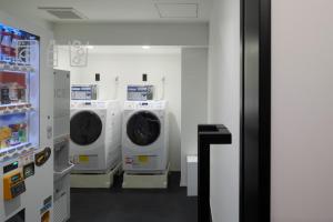 a laundry room with four washing machines and a refrigerator at hotel androoms Nagoya Fushimi in Nagoya