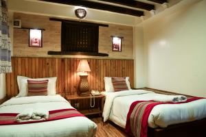 a bedroom with two beds and a table with a lamp at Nepal Pavilion Inn in Kathmandu