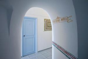 an archway leading to a white hallway with a blue door at Katerina's Castle - Caldera Cave Hotel in Imerovigli