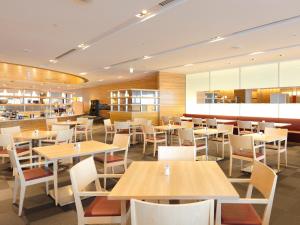 a restaurant with wooden tables and white chairs at Haneda Excel Hotel Tokyu Haneda Airport Terminal 2 in Tokyo