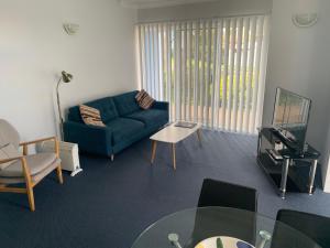 sala de estar con sofá azul y mesa en Aquarius Apartments Mollymook en Mollymook