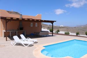a swimming pool with two chairs and a house at Casa Caliche in La Lajita
