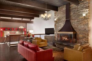 a living room with a fireplace and red chairs at Ramada by Wyndham Spokane Airport in Spokane