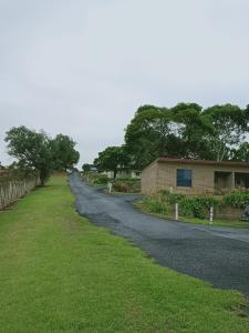 a road next to a building and a grass field at Limestone Coast Tourist Park in Mount Gambier