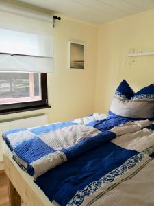 ein Bett mit blauen und weißen Decken und einem Fenster in der Unterkunft Haus Andrea in Himmelpfort
