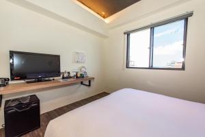 um quarto com uma cama, uma televisão e uma janela em Traveller Inn Tiehua Cultural and Creative Hotel II em Taitung City