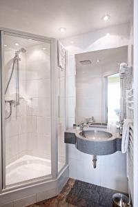 a bathroom with a glass shower and a sink at Hotel Perekop in Berdorf