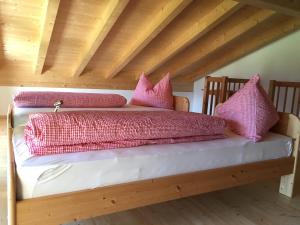 a bed with pink pillows on top of it at Bauernhof Residence Hausergut in Sluderno