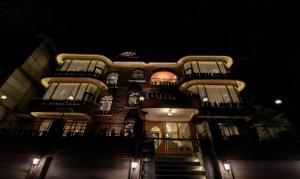 奈尼塔尔Hotel Lakeside Inn Nainital的一座高大的建筑,晚上有楼梯和阳台