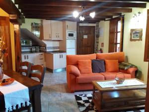 sala de estar con sofá naranja y cocina en Apartamentos La Condesa, en Valmeo