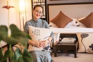 Una donna che tiene un pezzo di carta in una stanza d'albergo di Peach Blossom Resort Hotel a Guilin