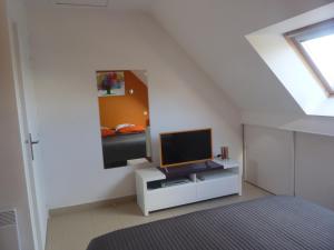 a bedroom with a television on a white cabinet with a mirror at Auprès de mon arbre in Saint-Gildas-de-Rhuys