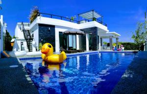 a yellow rubber duck in a swimming pool in front of a house at @CHAIN Pool Villa in Hua Hin