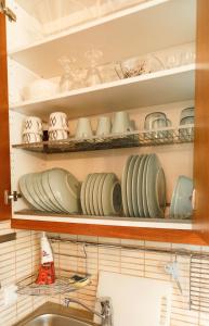 a shelf filled with plates and cups and a sink at Villa de pikku Maria in Hamina