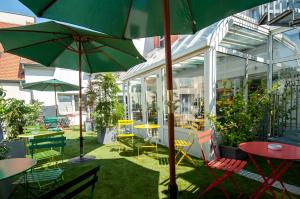 a patio with tables and chairs and umbrellas at La Maison Hôtel Mulhouse Centre in Mulhouse